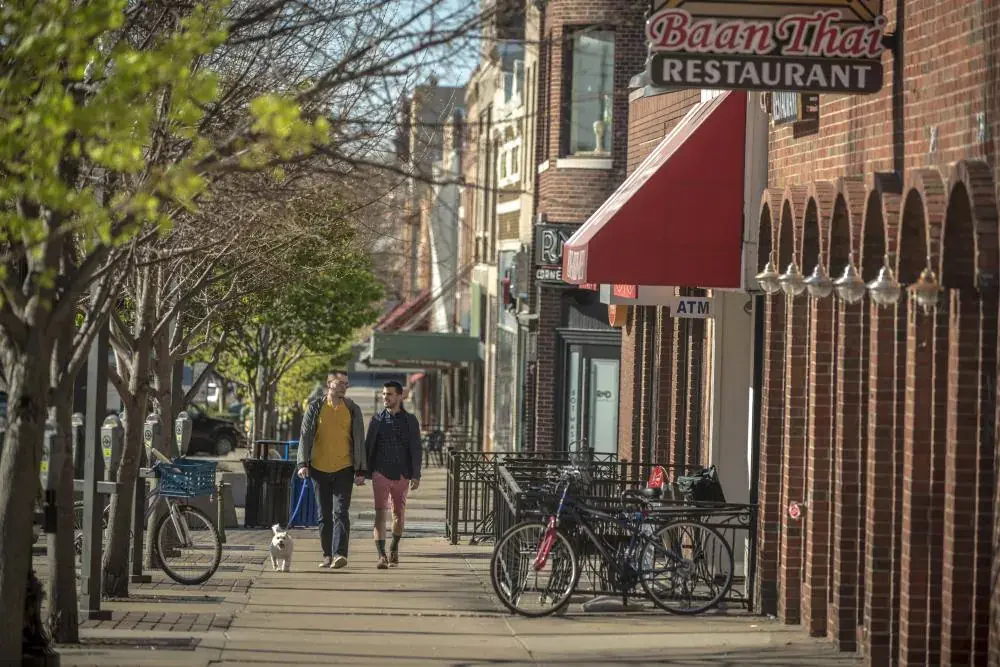 Two people walking a dog along Massachusetts Street in downtown Lawrence, KS