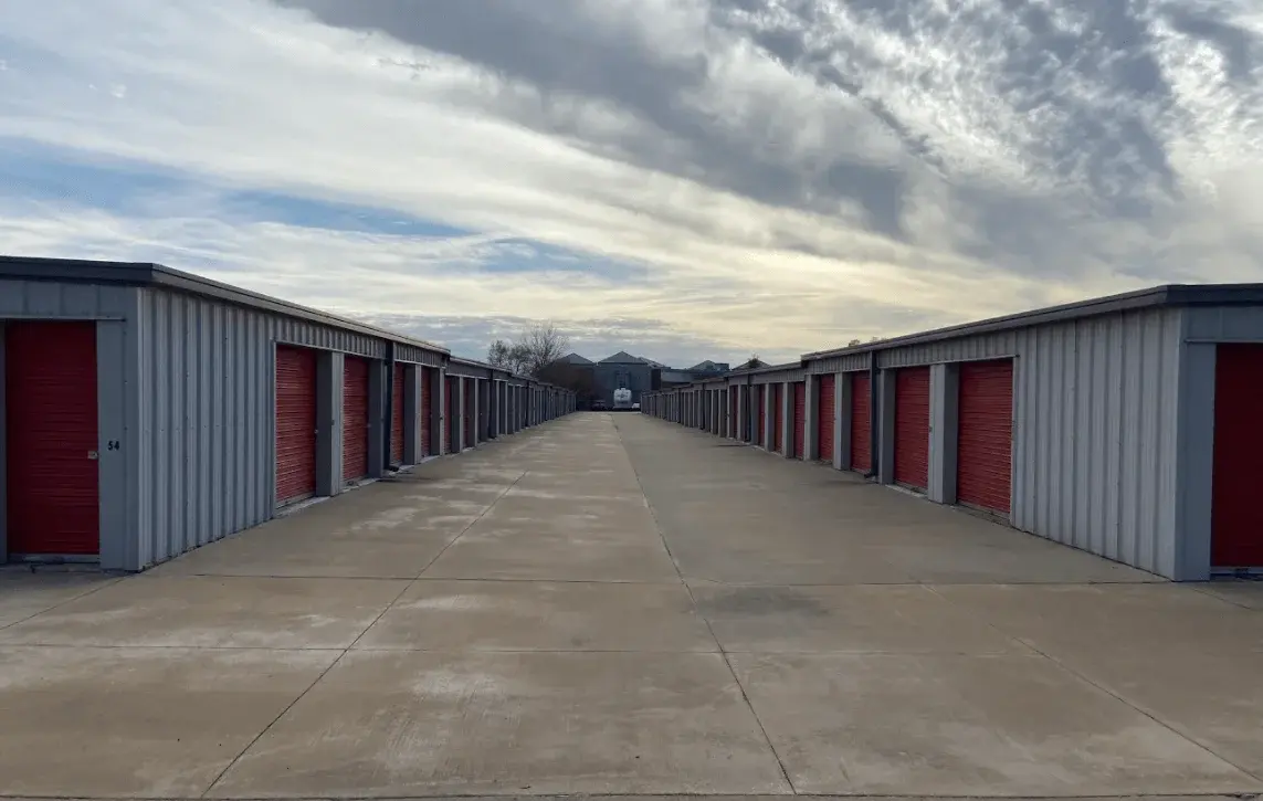 Wide concrete drive aisle between rows of red-door drive-up units at Free State Storage in Lawrence, KS